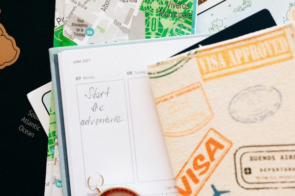Flat lay of travel essentials including compass, notebook, and map for a journey.
